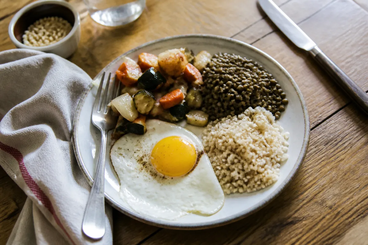 Assiette équilibrée avec légumes, lentilles, céréales complètes et œuf